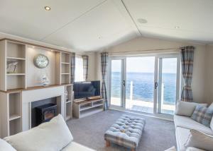 a living room with a fireplace and a view of the ocean at Bennane Shore Holiday Park in Lendalfoot