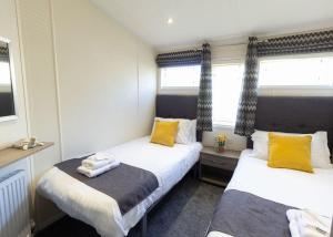 two beds in a small room with yellow pillows at Bennane Shore Holiday Park in Lendalfoot