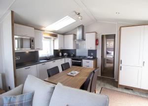 a kitchen with a wooden table and a dining room at Bennane Shore Holiday Park in Lendalfoot