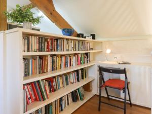 a book shelf filled with books next to a chair at The Old Barn in Colyton