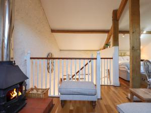 a living room with a fireplace and a bedroom at The Hay Loft in Colyton