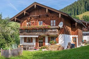 a wooden house with flowers in front of it at Bergbauernhof Simmerl in Sachrang