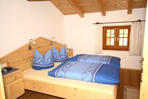 um quarto com uma cama com almofadas azuis em Bergbauernhof Simmerl em Sachrang