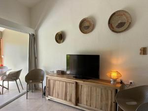 sala de estar con TV de pantalla plana en un centro de entretenimiento de madera en - Les pieds dans l'eau à 50m de la plage, côté mer caraïbe - Domaine de l'Anse CARITAN - Sainte-Anne -, en Sainte-Anne