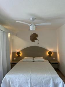 Un dormitorio con una cama blanca con ventilador de techo. en - Les pieds dans l'eau à 50m de la plage, côté mer caraïbe - Domaine de l'Anse CARITAN - Sainte-Anne -, en Sainte-Anne