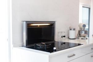 a white kitchen with a black stove top oven at Penthouse with jacuzzi and sea view, Morabeza Deluxe in Mindelo
