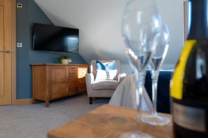 a living room with a tv and a chair and wine glasses at Stunning rural stay with idyllic views & great location in Talacre