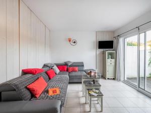 a living room with a gray couch and red pillows at Charmante maison avec piscine partagee in Le Bois-Plage-en-Ré