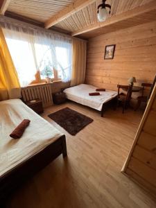 a room with two beds and a table and a chair at Dom Wypoczynkowy Anetka in Białka Tatrzańska