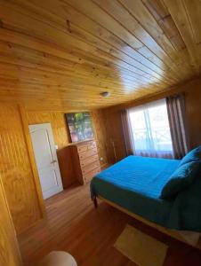 ein Schlafzimmer mit einem blauen Bett in einem Holzzimmer in der Unterkunft Casona los boldos in Santa Cruz