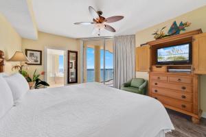 um quarto com uma cama branca e uma televisão em Beach Colony East 13C em Perdido Key
