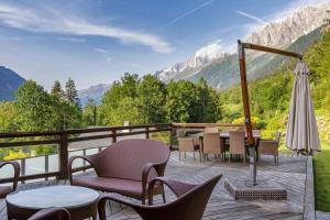a deck with chairs tables and an umbrella and mountains at Chalet Galadhrim Chamonix Mont Blanc Valley in Les Houches