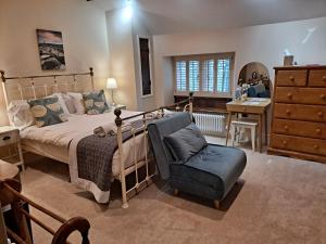 a bedroom with a bed and a chair and a dresser at Robin Hood Farm B&B in Baslow