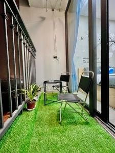 Duas cadeiras e uma mesa numa varanda com relva em Layla House -2905 G3 Vinhomes Greenbay em Hanói