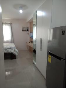 Zimmer mit einem Kühlschrank und einem Schlafzimmer mit einem Bett. in der Unterkunft Cozy1233 studio at The Persimmon in Cebu City