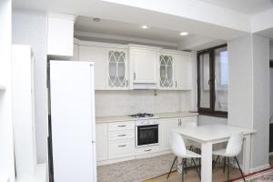 eine Küche mit weißen Schränken und einem Tisch mit Stühlen in der Unterkunft Апартаменты в центре Бишкека in Bischkek + 13 Fotos