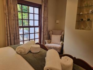 Cette chambre comprend un lit, une fenêtre et une chaise. dans l'établissement Schuilhoek Garden Terraces, au Cap