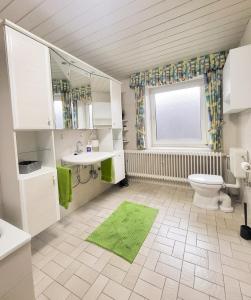 a bathroom with a toilet and a sink and a window at Ferienwohnung Meyer in Surwold