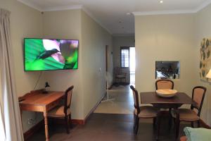 a living room with a table and a television on the wall at Schuilhoek Garden Terraces in Cape Town