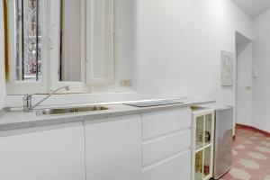 a white kitchen with a sink and a window at Charming Colosseum in Rome