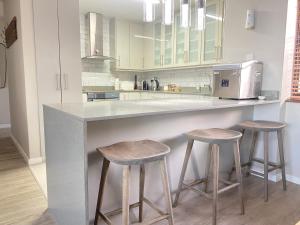 a kitchen with two stools and a counter with a microwave at Rosebud 4 Beacon Point in Mossel Bay