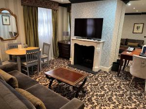 uma sala de estar com um sofá e uma lareira com uma televisão em The Leonard Hotel em Londres