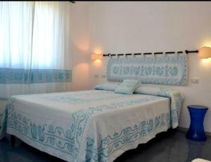 a bedroom with a bed with a blue and white blanket at Villa Pischinas in Magomadas