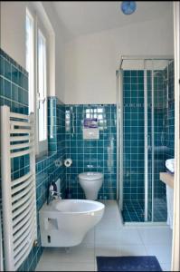 a blue tiled bathroom with a sink and a toilet at Villa Pischinas in Magomadas