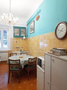 cocina con mesa y reloj en la pared en Casa Antica - Historical apartment in old city center, en Trieste