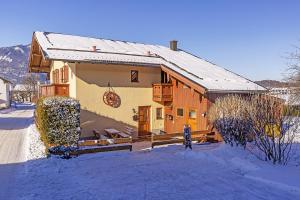 una pequeña casa con nieve en el suelo en Chiemgauferienwohnungen - Wanderlust und Alpenrose, en Unterwossen