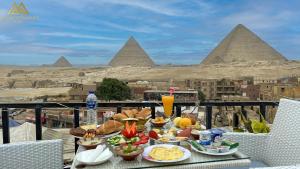 カイロにあるGolden Pyramids View Innのピラミッドを背景にテーブルの上に食料品を並べたトレイ