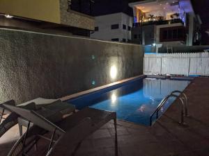 einen Pool in der Nacht mit einem Tisch und Stühlen in der Unterkunft Harbor Pond Apartments 2 in Lagos