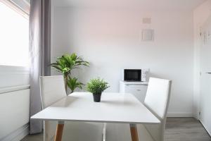 mesa de comedor blanca con 2 sillas y microondas en La maruca loft, en Santander