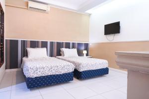 two beds in a room with a tv on the wall at Guesthouse Phuket Airport in Ban Bo Han