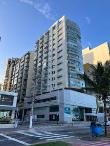 a tall building with a palm tree in front of it at Loft com vista incrível para a Praia da Costa! in Vila Velha