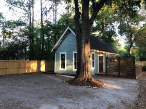 una pequeña casa con un árbol al lado de una valla en Cozy Island Cottage, en Charleston