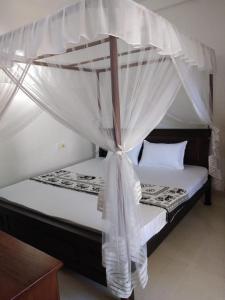a bedroom with a bed with a canopy at Prasai House in Ahangama