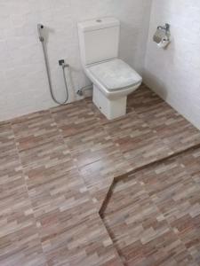 a bathroom with a toilet and a wooden floor at Prasai House in Ahangama
