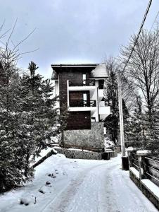 a snow covered road with a building in the background at Casa Larisa - Wolves Apartment in Sinaia