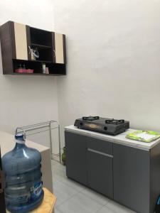 uma cozinha com uma garrafa de água e um fogão em Homestay Syariah Orchard Family D30 em Sengkaling