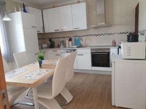 a kitchen with a wooden table and white cabinets at Alojamento Local Terreiro in Pombal