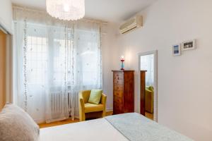 una camera con letto, sedia e specchio di Galleria Eremitani Exclusive Elegant Apartment a Padova