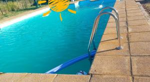 a pool with blue water and a metal hand rail at Piscinas y cabañas san antonio in Los Ángeles