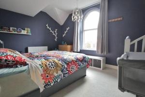 - une chambre avec des murs bleus et un lit avec un couvre-lit coloré dans l'établissement Retro penthouse flat, close to parks and centre, à Liverpool