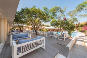 un patio con sofás, mesas y una piscina en Filerimos Village Hotel, en Ialisos