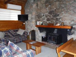 a living room with a stone fireplace and a couch at 81 on Freycinet in Coles Bay