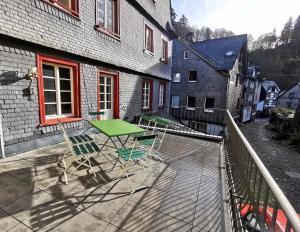 a patio with a green table and chairs on a balcony at Ferienwohnung To Hous in Monschau
