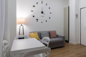 a living room with a couch and a clock on the wall at Nuovo intimo APT a 10min dal Duomo - HomeUnity in Milan