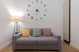 a couch in a living room with a clock on the wall at Nuovo intimo APT a 10min dal Duomo - HomeUnity in Milan