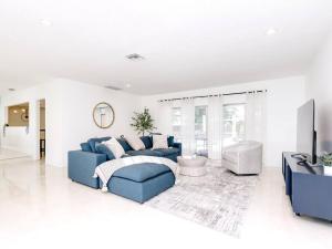 a living room with a blue couch and a tv at Modern Spacious 5-Bedroom Home with Pool in Hollywood